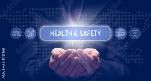 Obraz na płótnie Businessmans cupped hands holding an Health and Safety business concept on a computerised display. w salonie
