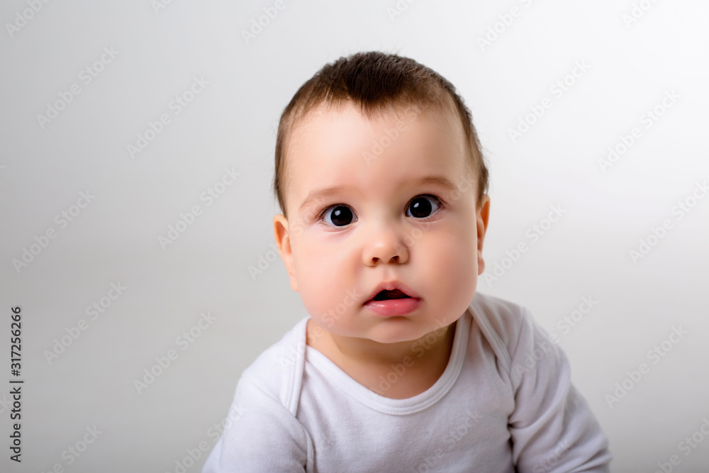 portrait of a baby boy looking at the camera in a white bodysuit on a white background, space for text portrait of a baby boy looking at the camera in a white bodysuit on a white background, space for text
