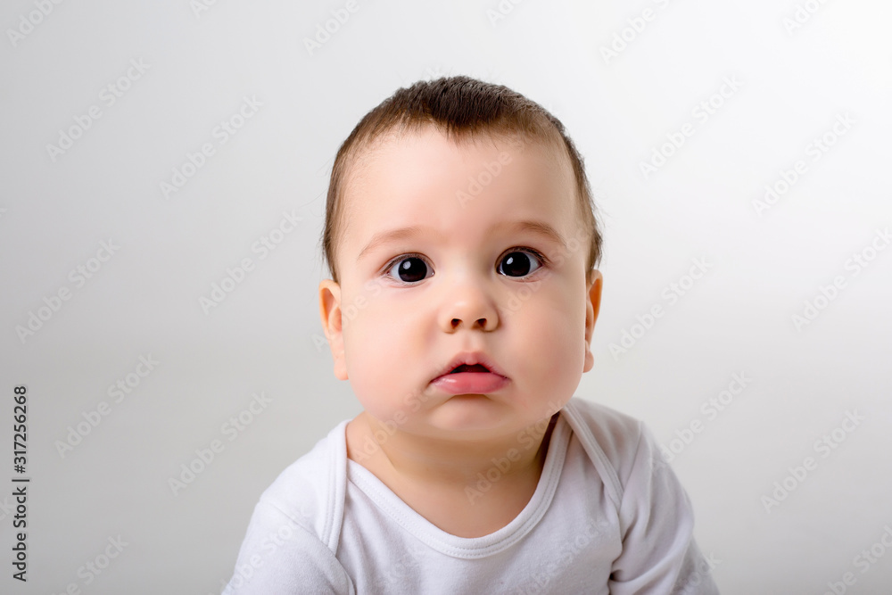 portrait of a baby boy looking at the camera in a white bodysuit on a white background, space for text portrait of a baby boy looking at the camera in a white bodysuit on a white background, space for text