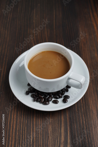 Black coffee in a white pitcher On an old wooden table