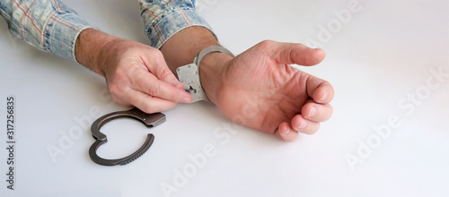 The criminal is released from prison. The acquittal was handed down to an innocent defendant. Hands unbuckling handcuffs. Open handcuffs on the male hands of the arrested person. photo