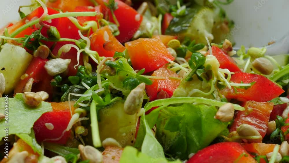 Close up of vegetable salad with green leaves and sprouts, variety sliced vegetables and seeds Close up of vegetable salad with green leaves and sprouts, variety sliced vegetables and seeds