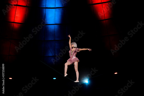 artistic aerial acrobat standing on rope performing in circus