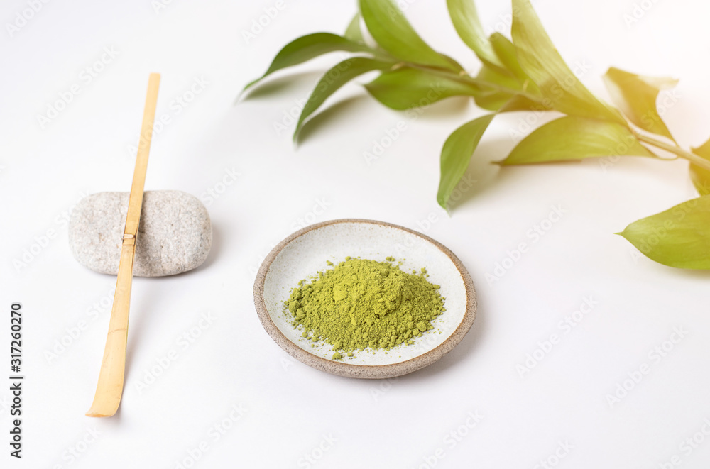 White ceramic spoon with tea of a match on a light gray background White ceramic spoon with tea of a match on a light gray background