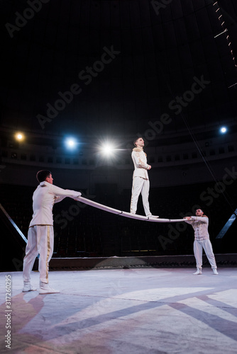 gymnast standing on pole near acrobats in circus