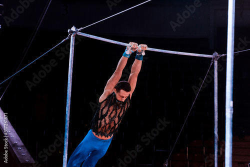 athletic man performing on horizontal bars in arena of circus © LIGHTFIELD STUDIOS