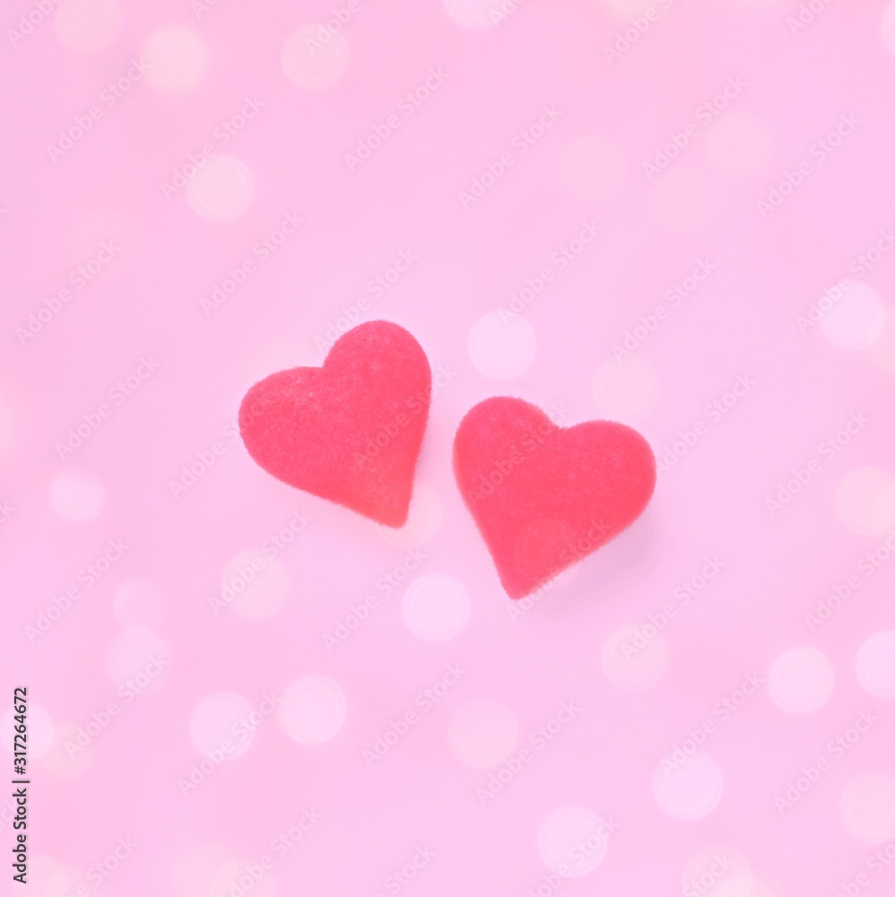 Two red hearts on a light pink blurry background with bokeh. Valentines Day greeting card. Concept of love, romance. Square, copy space for text.
