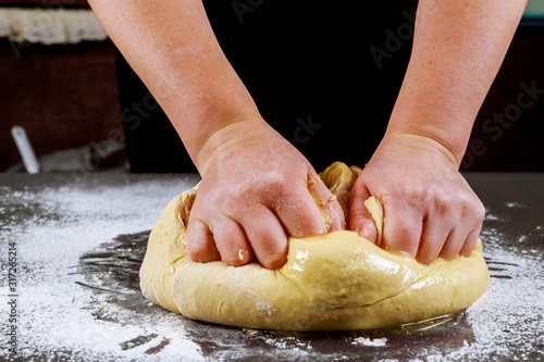 Woman kneading dough for making pizza.