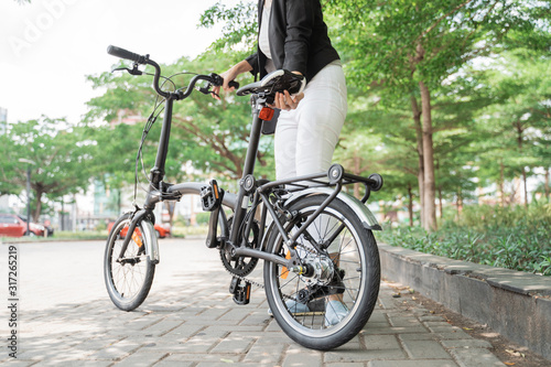 asian woman worker holding her folding bike when go to office