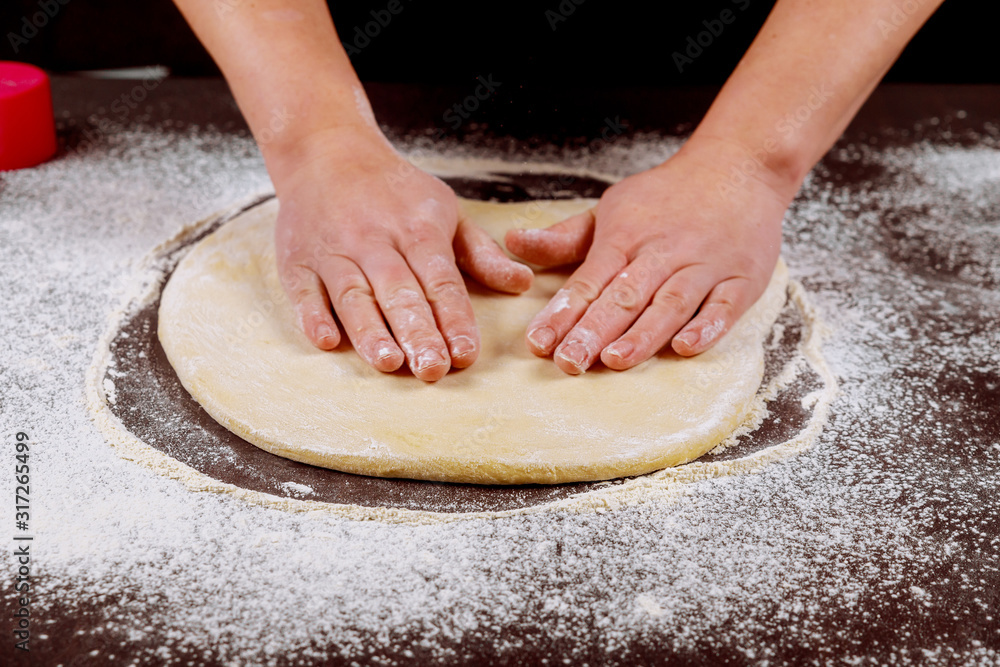 Woman smoothes yeast dough with her hands. Woman smoothes yeast dough with her hands.
