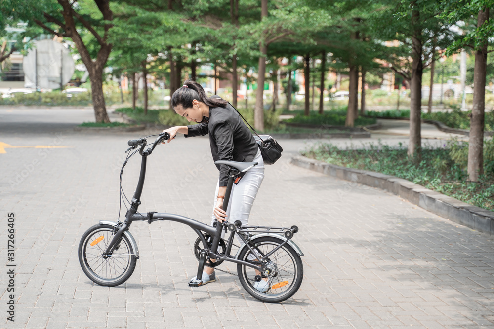 asian woman worker holding her folding bike when go to office asian woman worker holding her folding bike when go to office