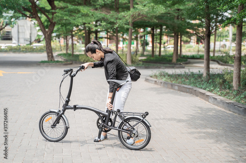 asian woman worker holding her folding bike when go to office