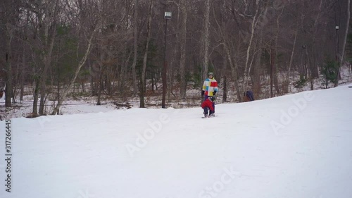 Young man snowboard instructor tiches little boy how to ride a snowboard. Winter activities concept. Slowmotion shot photo