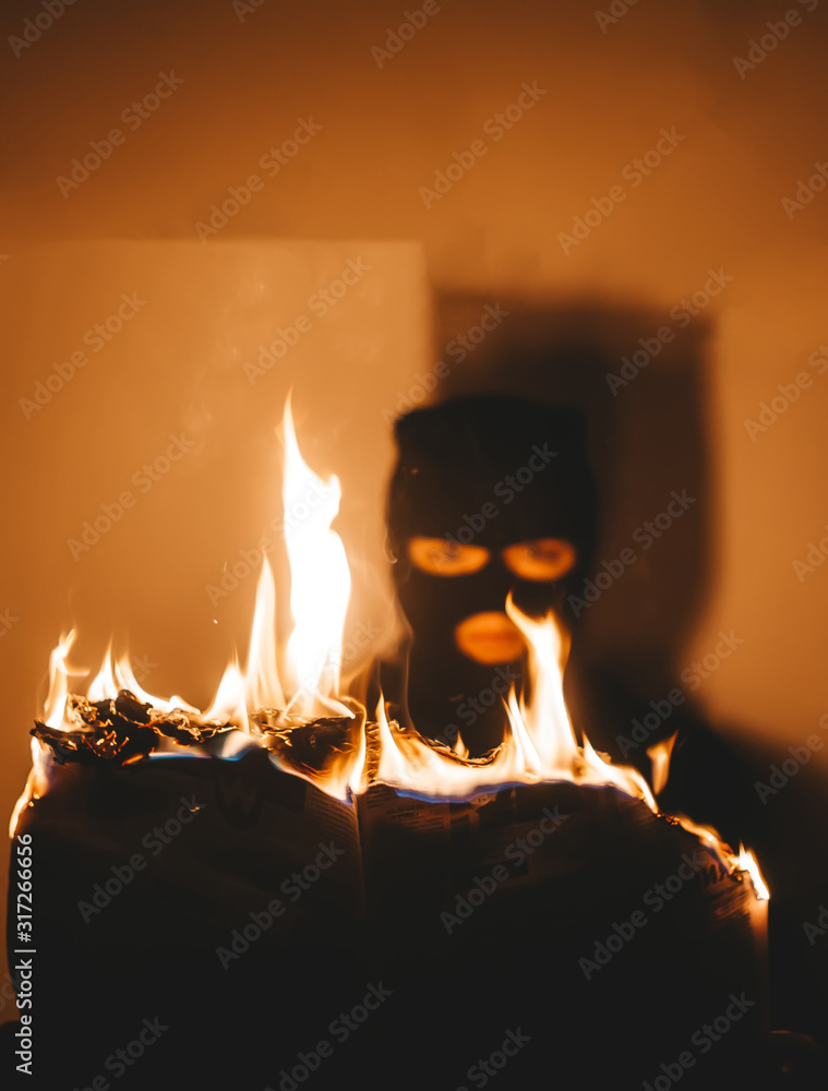Beautiful desperate young woman wearing black hijab burns the newspaper.
