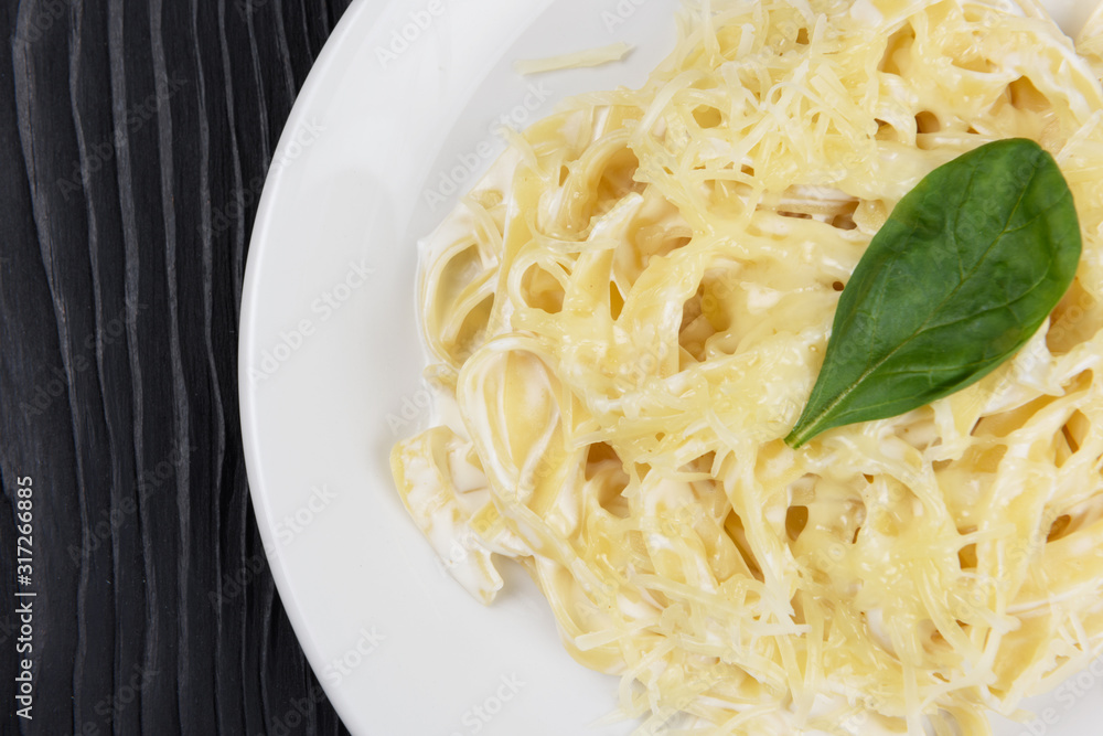 Pasta with sauce and basil in plate on black wooden background Pasta with sauce and basil in plate on black wooden background
