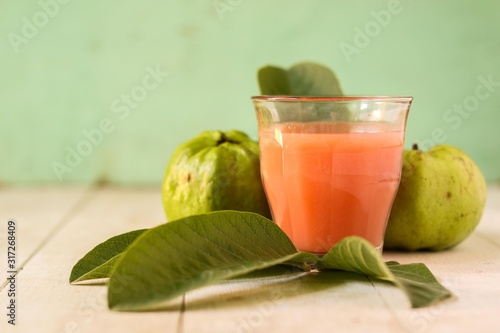 A glass of Guava Juice with fresh Guava fruit slices isolated on wooden background photo