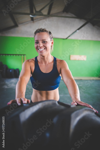 Fototapeta Naklejka Na Ścianę i Meble -  Female fitness model doing cross fit exercise with a massive tyre in a gym