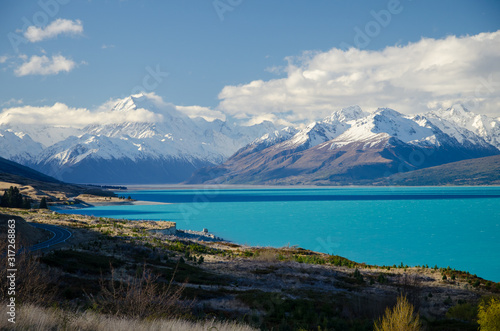 Snow covered Mount Cook with Lake Pukaki in the foreground and blue sky and white clouds, South Island, New Zealand