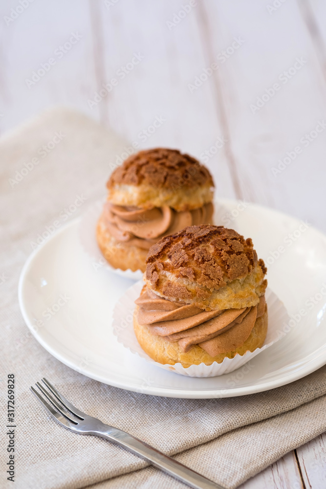 Homemade choux cream or cream puffs with tea cream on wooden background.