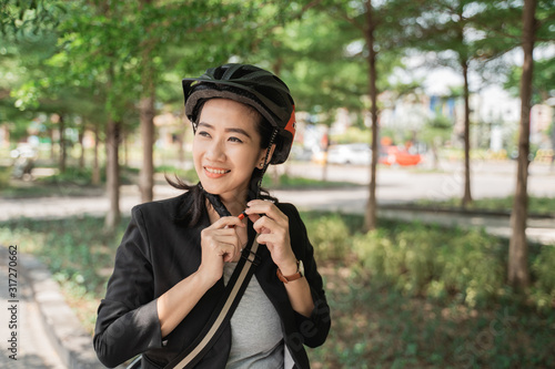 smiling woman wearing helmet for safety when go by bike to work in the morning