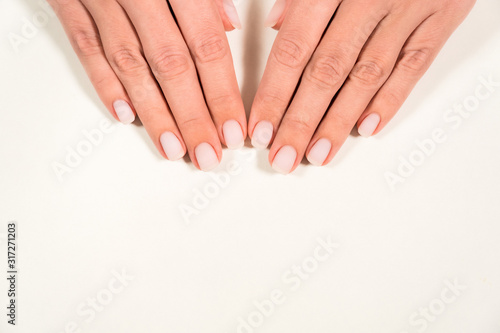 Closeup top view color photography of two beautiful female hands with modern trendy pastel natural manicure naildesign covered with finish mat top without gloss. 
