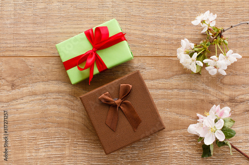 Gift boxes with cherry flowers on the wooden background.