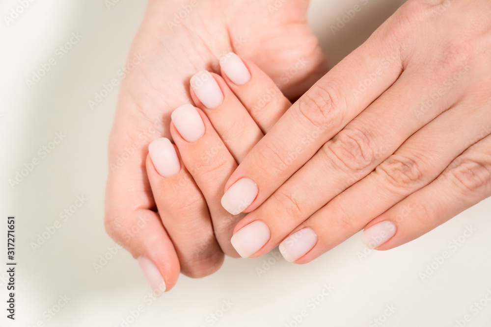 Closeup top view color photography of two beautiful female hands with modern trendy pastel natural manicure naildesign covered with finish mat top without glance. Closeup top view color photography of two beautiful female hands with modern trendy pastel natural manicure naildesign covered with finish mat top without glance.