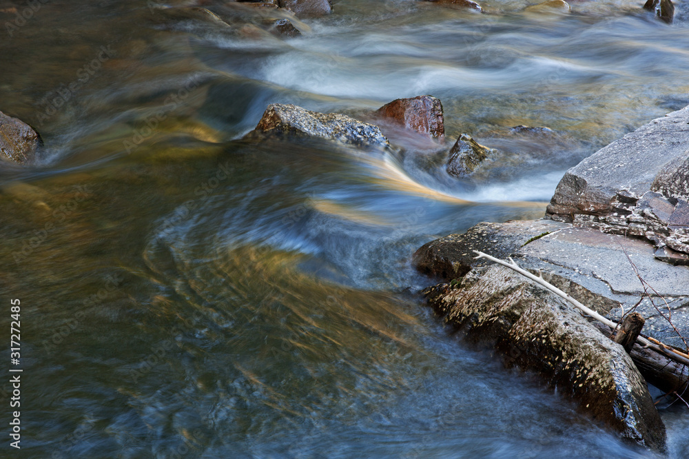 Spring landscape of the Little River rapids captured with motion blur and illuminated with reflections from sunlit foliage and blue sky overhead, Great Smoky Mountains National Park, Tennessee, USA Spring landscape of the Little River rapids captured with motion blur and illuminated with reflections from sunlit foliage and blue sky overhead, Great Smoky Mountains National Park, Tennessee, USA