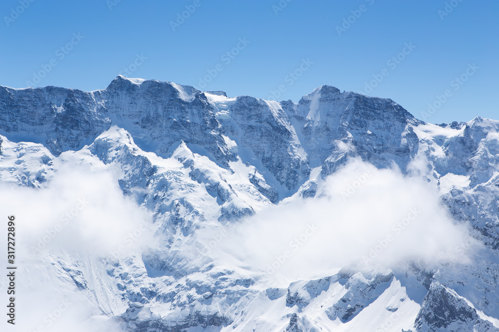 Winter landscape, Mountains covered by snow with mist flow through mountains in sunnyday winter in Switzerland
