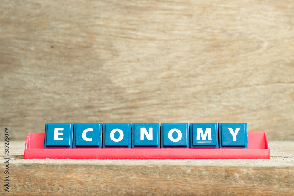 Tile letter on red rack in word economy on wood background Tile letter on red rack in word economy on wood background