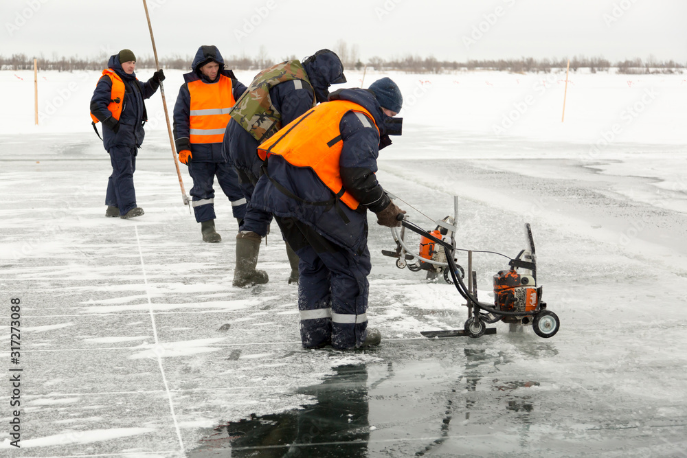 Workers cut ice blocks to the size of ice on a frozen lake