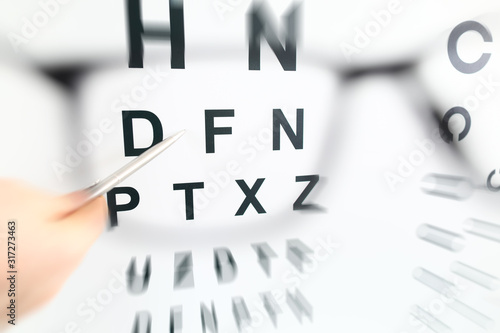 Silver pen pointing to letter in check table through eyeglasses
