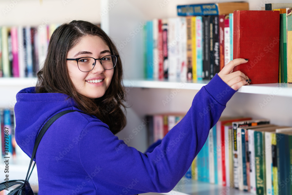 Intellectual Teenage girl choose books and pick them from a library or bookstore. Intellectual Teenage girl choose books and pick them from a library or bookstore.