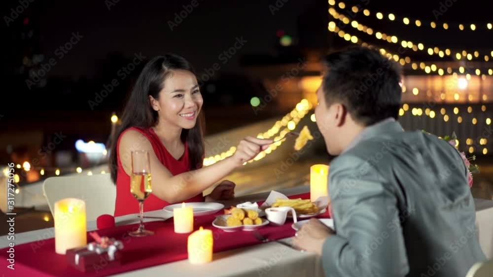 HD Slow motion Happy Asian couple beautiful woman enjoying dinner date with boyfriend on rooftop restaurant in romantic city night. Couple romantic dinner and valentine day celebration concept. HD Slow motion Happy Asian couple beautiful woman enjoying dinner date with boyfriend on rooftop restaurant in romantic city night. Couple romantic dinner and valentine day celebration concept.