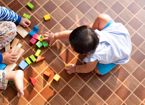 Canvas Print Little asian girl playing with wood blocks on the floor