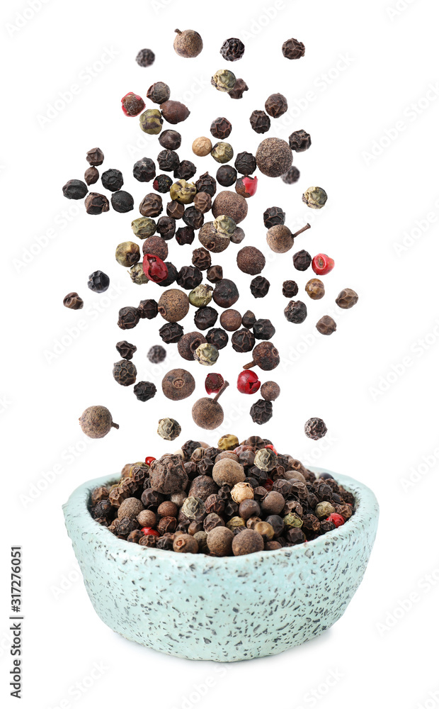 Different peppercorns falling into bowl on white background
