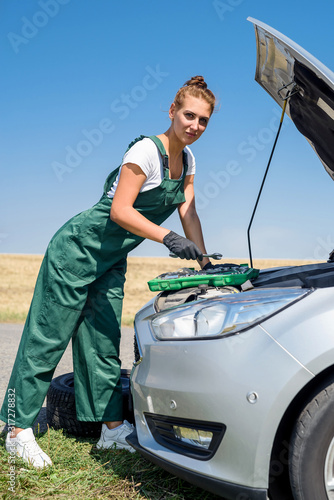 Beautiful European woman repairs the car on the road.