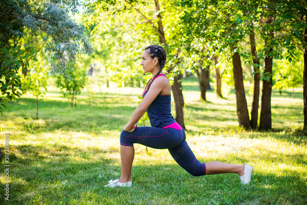 Sports woman doing exercises for stretching the legs, sits on the splits. In the park on the lawn. Sports woman doing exercises for stretching the legs, sits on the splits. In the park on the lawn.