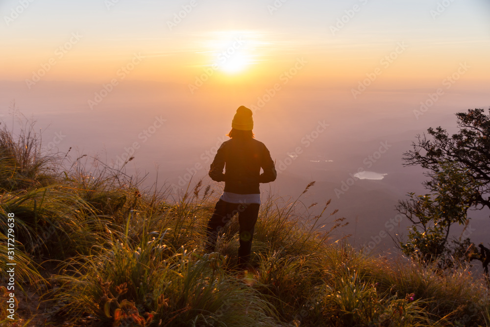 rear of happy woman stand on top mountain looking view with sunrise and mist at  (Doi Norg Doi Luang National Park) Phayao province. soft focus.