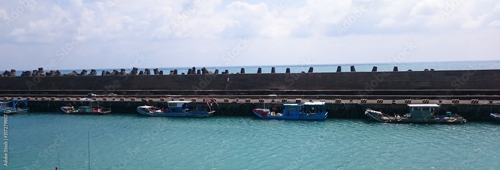 Blue boats in the sea behind a dam Blue boats in the sea behind a dam