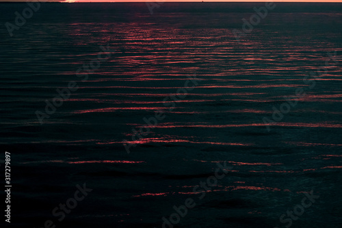 View of the high seas with small waves and reflection of the rays of the setting sun