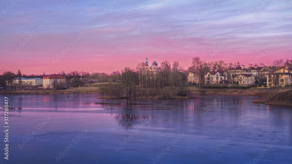 Panorama of a purple sunset with a rural landscape with houses on the lake.