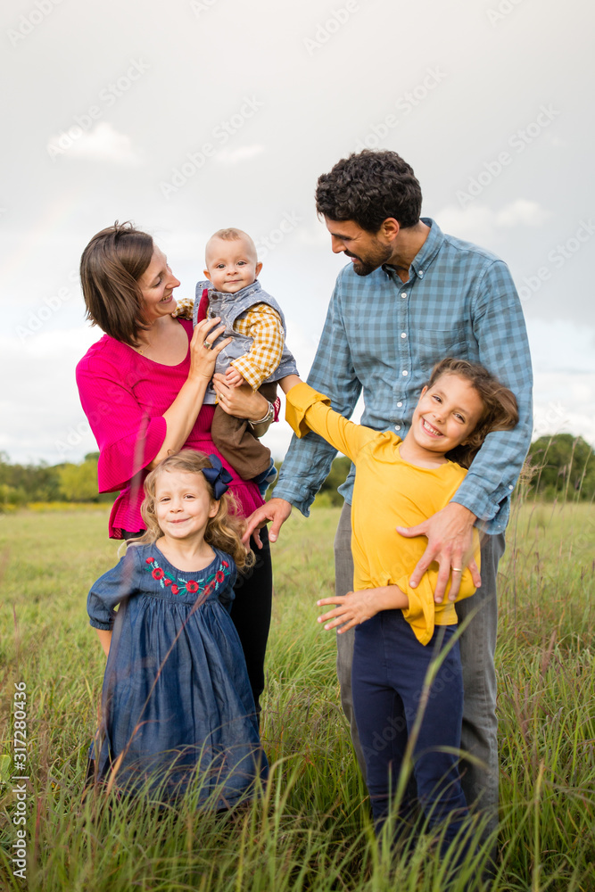 Portrait of young smiling family holding a baby outdoors Portrait of young smiling family holding a baby outdoors