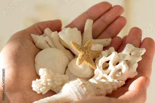 young woman holding white sea shells and corals