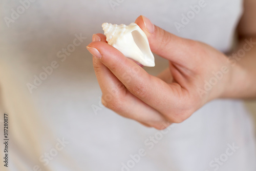 white sea shell in a woman's hand on white background