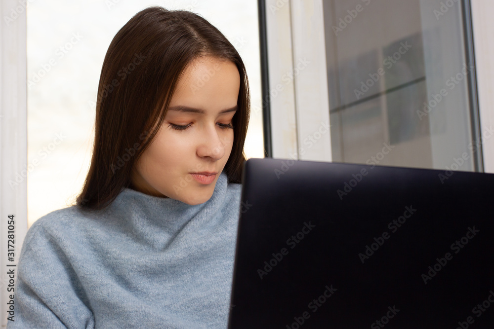 Nice European girl at home sitting at a laptop, working, shopping Nice European girl at home sitting at a laptop, working, shopping