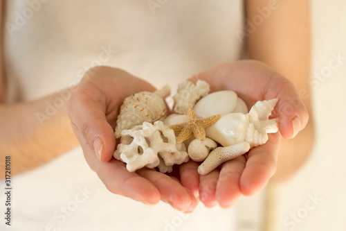 young woman holding white sea shells and corals