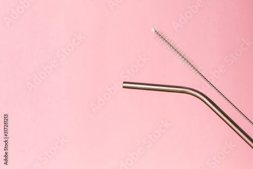Metal, bendy drinking straw and steel cleaning brush on pink background. Aluminum stainless reusable bar equipment for drink alcohol cocktails, water or lemonade. Eco friendly alternative