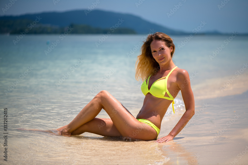 Young slim beautiful girl sits and relaxes in the sea or ocean waves