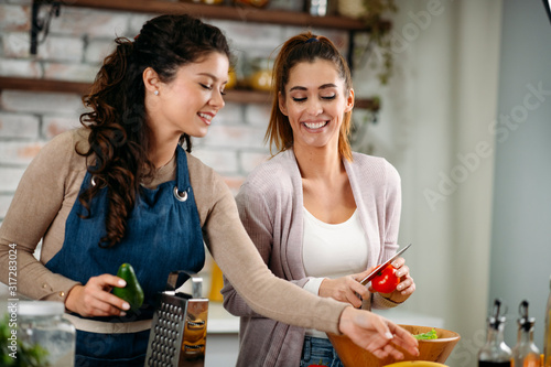 Two friends having fun in kitchen. Sisters cooking together. 